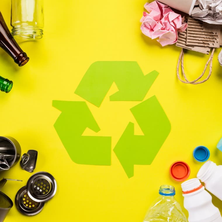 Tomma förpackningar mot en gul bakgrund med en grön återvinningssymbol i mitten.