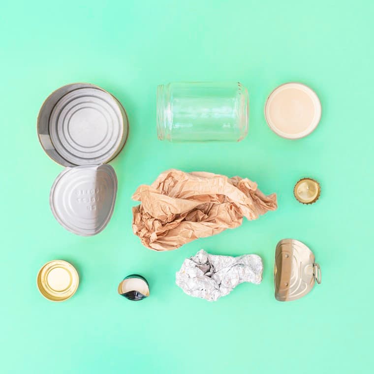 Tomma förpackningar av flera materialslag mot en turkos bakgrund.