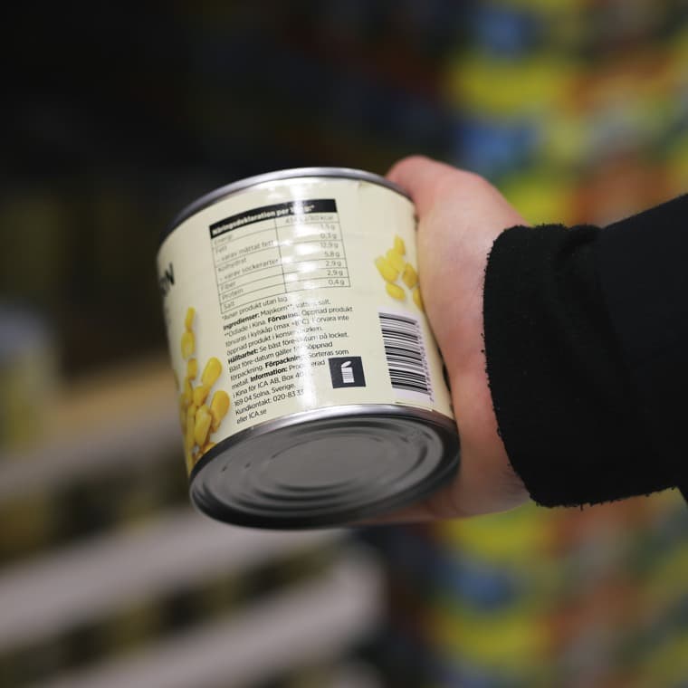 En hand håller i en metallförpackning med sorteringsmärkning på.