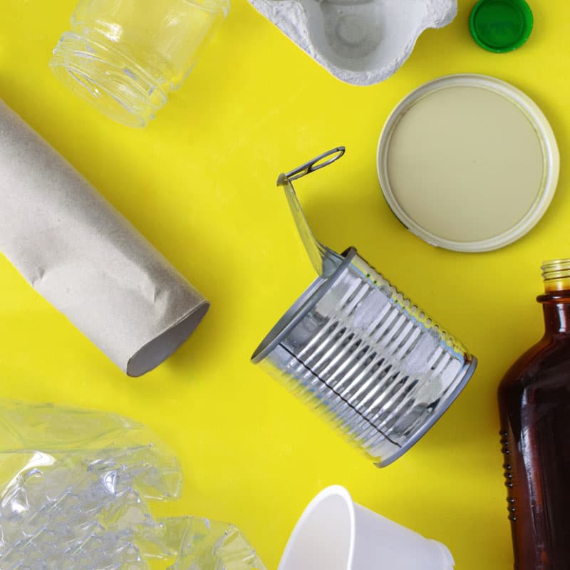 Förpackningar i olika materialslag mot en gul bakgrund.