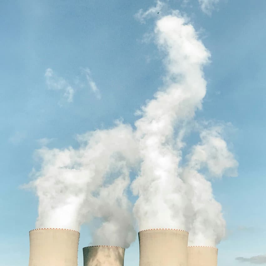 Vit rök som stiger upp ur fyra skorstenar.