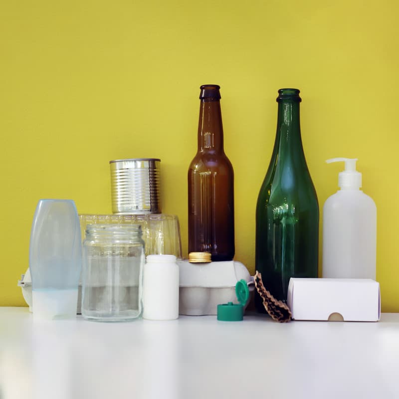 Förpackningar i olika materialslag mot en gul bakgrund.