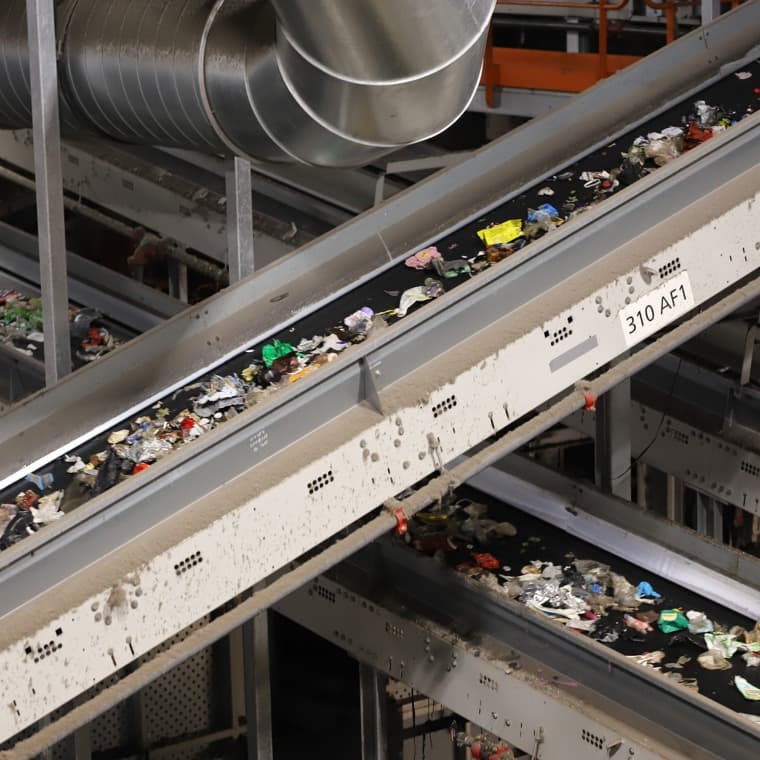Förpackningar transporteras på band i en sorteringsanläggning.