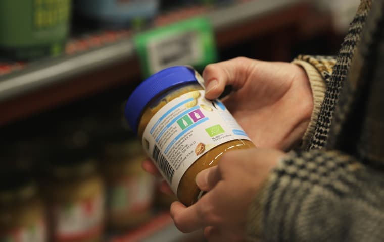 En hand håller i en förpackning med sorteringsmärkningar på.